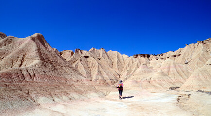 A person walks through Las Bardenas Reales, Natural Reserve and Biosphere Reserve, Navarra, Spain