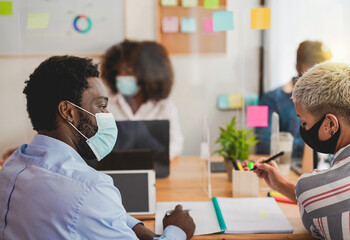 Obraz premium Young multiracial people at work in office while wearing protective face mask for coronavirus - Work places with new safety measures