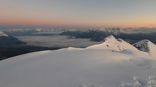 View of gorgeous pink sunrise over glacier and high mountain peaks in the Alps. The cross on top of the mountain Nockspitze. Innsbruck and the Alps are seen from the Mount. 