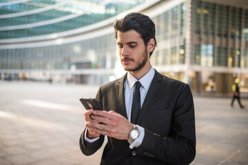 Businessman holding mobile smartphone using app texting sms message