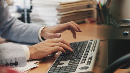 young man works at laptop sitting at table in home office. looking for needed information, nodes and smiles. start typing on keyboard © GRAFStock