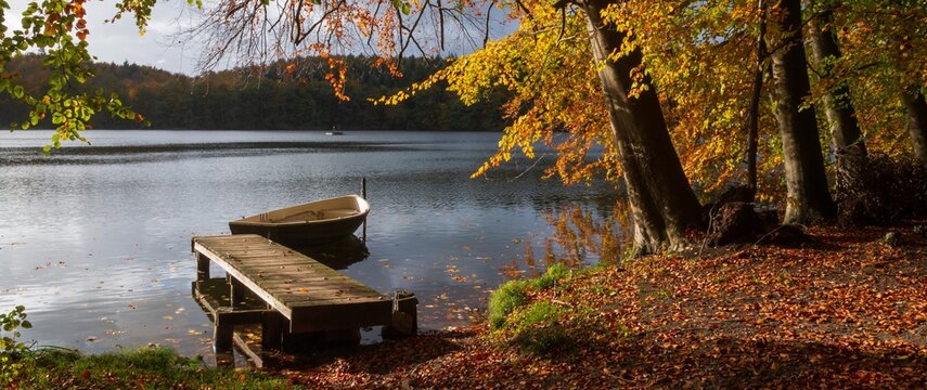 Idylle am See mit Steg und Boot im Herbst