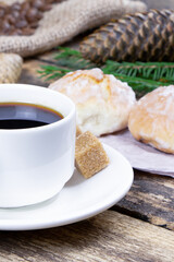 A cup of coffee and cake on a wooden background. Green fir branch on a wooden table. Cane sugar. A cup of espresso.