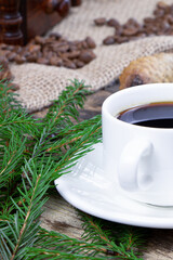 A cup of coffee and cake on a wooden background. Green fir branch on a wooden table. Cane sugar. A cup of espresso.