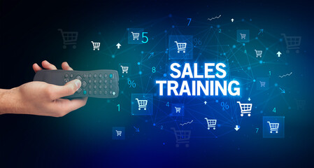 hand holding wireless peripheral with SALES TRAINING inscription, online shopping concept