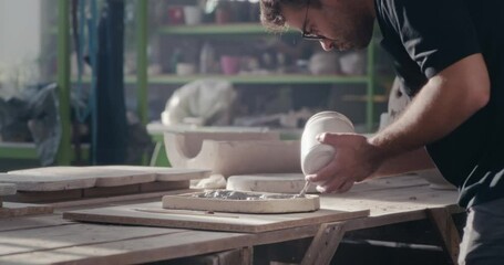 Male ceramist painting handicraft in studio