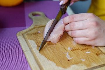 woman cuts of chicken on a cutting board