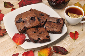 brownie pieces with cherries and tea cup on a wooden background