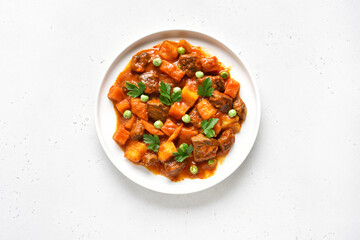 Homemade beef stew with potatoes and carrots in tomato sauce on  white plate