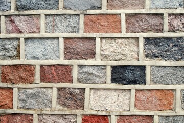 A fragment of a wall structure made of multi-colored stone bricks.
