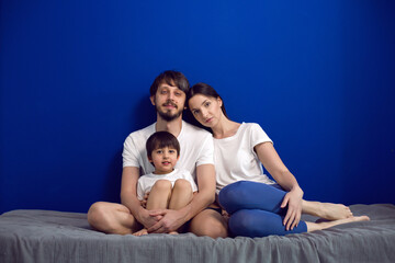 family mom dad son sitting on the bed at home