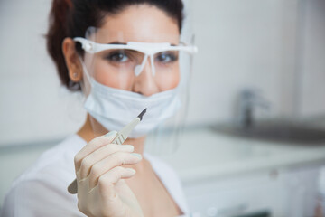 Female stomatologist ready for dental surgery, holding scalpel. Toothcare concept. Dentist at clinic office. Toothcare concept