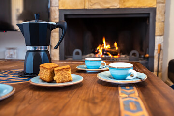 Coffee cups with coffee pot and lit fireplace