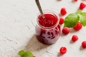 homemade raspberry jam on a concrete background with fresh raspberries, selective focus