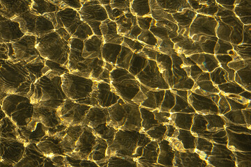Sun streaks on the sandy seabed. Shallow water on a sunny day. Morning sun. Close-up.