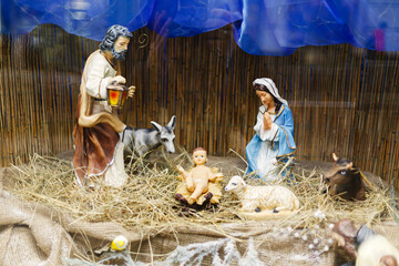 Fototapeta na wymiar Nativity scene, holy family figurines on hay. Birth of savior Jesus Christ, Christmas essence