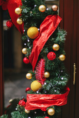Fototapeta premium Stylish christmas branches with red and gold baubles, modern ornaments on storefront or facade