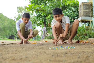 Indian child playing with glass marbles which is an old Indian village game. Glass Marbles are also...