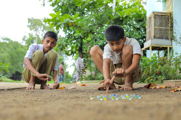 Indian child playing with glass marbles which is an old Indian village game. Glass Marbles are also...