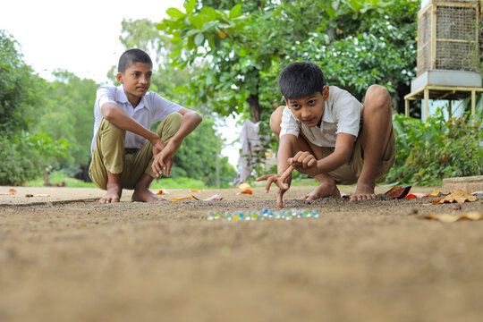 Indian child playing with glass marbles which is an old Indian village game. Glass Marbles are also called as Kancha in Hindi Language.