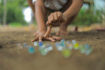 A child playing with glass marbles which is an old Indian village game. Glass Marbles are also called as Kancha in Hindi Language.