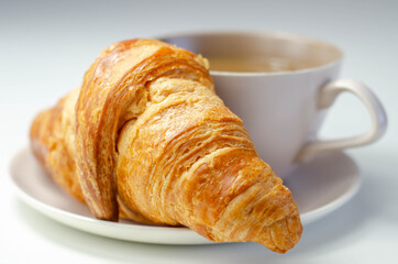 Croissant with chocolate on a plate with coffee in a cup