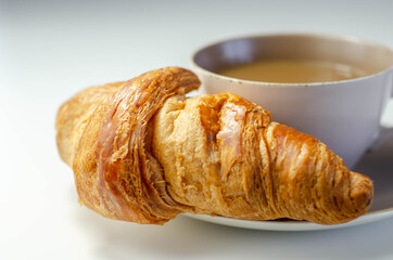 Croissant with chocolate on a plate with coffee in a cup