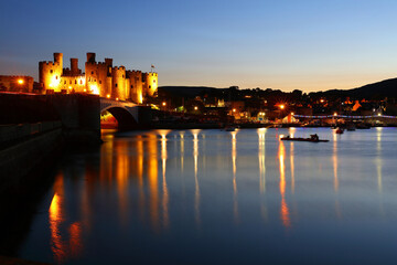 Fototapeta premium Conwy Castle floodlit against a blue Sky after Sunset, Conwy, North Wales, UK.