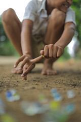 A child playing with glass marbles which is an old Indian village game. Glass Marbles are also called as Kancha in Hindi Language.