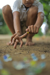 A child playing with glass marbles which is an old Indian village game. Glass Marbles are also called as Kancha in Hindi Language.