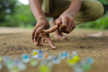 A child playing with glass marbles which is an old Indian village game. Glass Marbles are also...