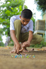 A child playing with glass marbles which is an old Indian village game. Glass Marbles are also...
