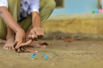 A child playing with glass marbles which is an old Indian village game. Glass Marbles are also called as Kancha in Hindi Language.