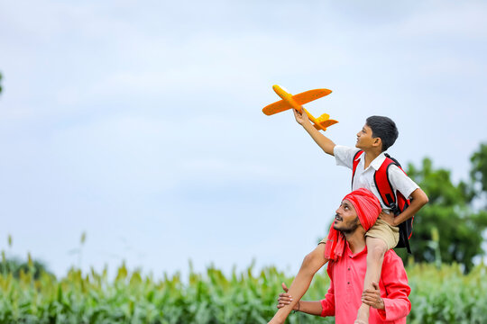 dreams of flight! indian child playing with toy airplane with his father on cycle