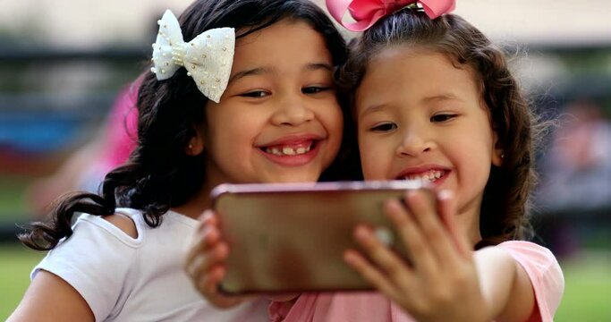 Two little girls posing for selfie with smartphone, children take photo with front camera