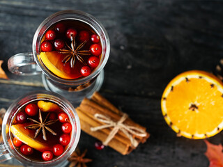 Two glasses of berry alcoholic mulled wine on a wooden table with cinnamon, orange, anise