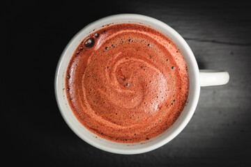 Fotografía cenital de una taza blanca llena de café con espuma cremosa tipo capuccino 