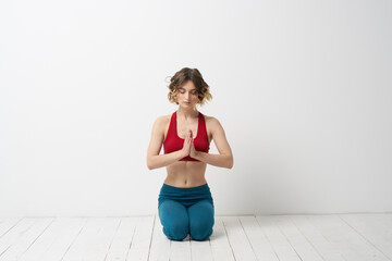 A woman in blue jeans practices yoga on a light background indoors and a slim figure in gymnastics