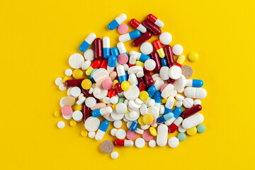 Many different pills on a yellow background. Medical concept.  Concept of threat of various diseases. Top view.