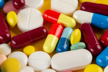 Many different pills on a yellow background. Medical concept.  Concept of threat of various diseases.