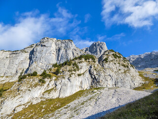 A close up view on a massive, stony mountains in Hochtor region, Austrian Alps. The steep slopes are barely overgrown with grass. Sharp peaks. Dangerous mountaineering. Sunny summer day. Adventure