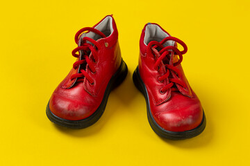 Children's leather shoes in red on a yellow background. Care for health.