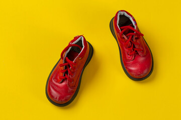 Children's leather shoes in red on a yellow background. Care for health.