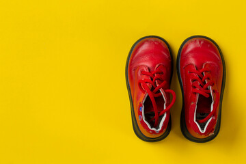 Children's leather shoes in red on a yellow background. Care for health.
