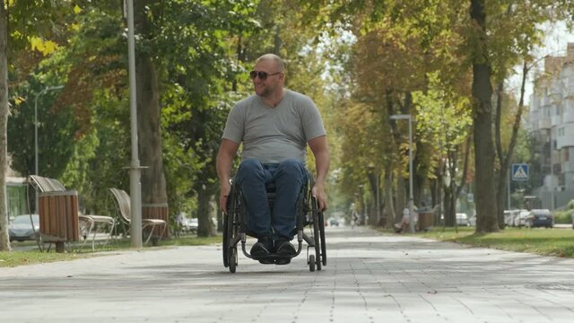 Handicapped man in wheelchair walk at the park alley