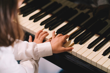 Fototapeta premium close up little kid with small hands playing grand piano