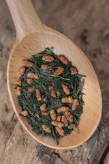 Green Japanese tea Genmaicha in a wooden spoon. A spoon on a wooden background. Close-up.