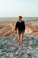 Portrait of a young blond man on a mountain in an orange sunset