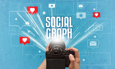 Fototapeta na wymiar Close-up of a hand taking photos with SOCIAL GRAPH inscription, social media concept