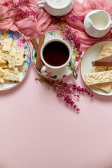 Hot chocolate or cocoa in cup with various sweets on sides. White chocolate bar and biscuits